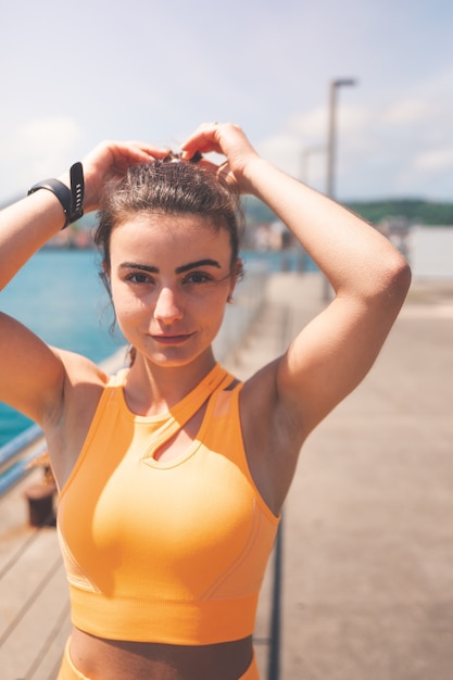 Young woman stretching with an orange sport set at the port