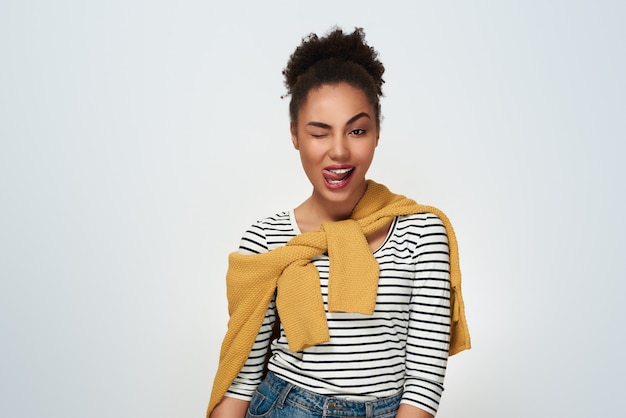 Young woman studio isolated in white winking showing tongue look