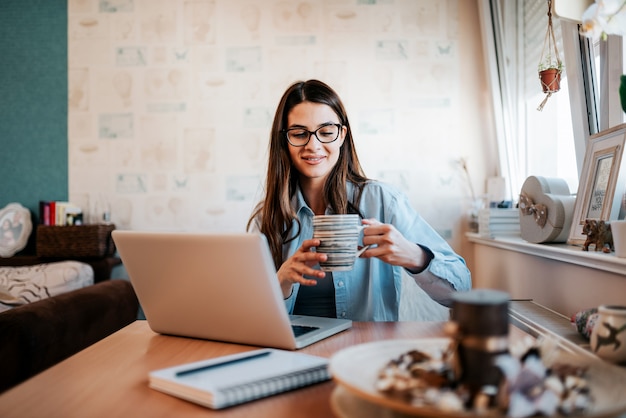 Young woman studying and drinking coffee in her apartment.