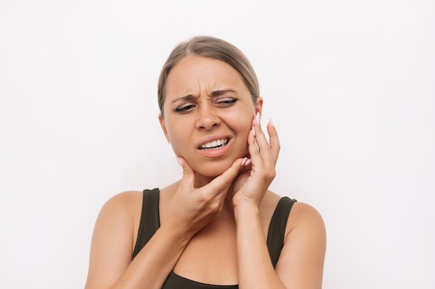 Young woman suffering from jaw pain holding her chin with hands Inflammation facial toothache