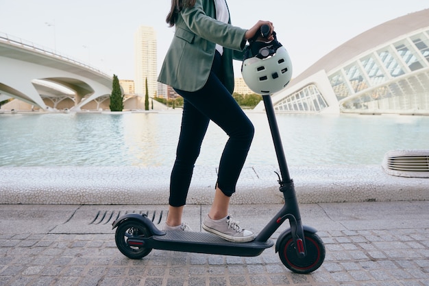 Young woman in suit driving an electric scooter