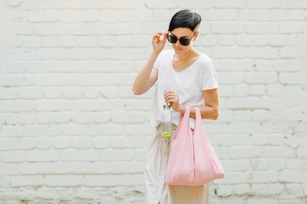 Young woman in  summer clothes with a eco bag and reusable water bottle. Sustainable lifestyle. Eco friendly concept.