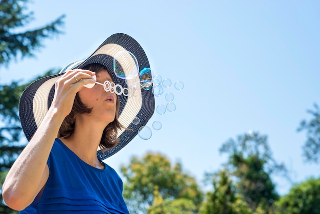 Young woman on summer holidays blowing soap bubbles