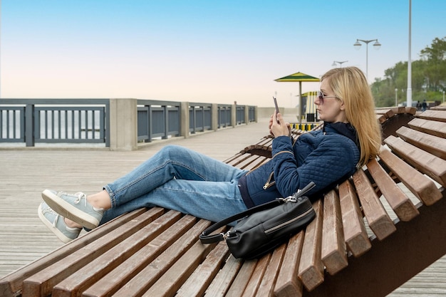 Young woman in a sun lounger uses a smartphone