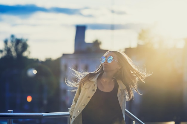 Young woman in sunglasses have fun with outdoor sunset in the background