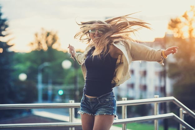 Young woman in sunglasses have fun with outdoor sunset in the background