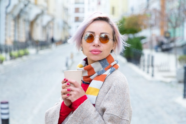 Young woman in sunglasses with a cup of coffee