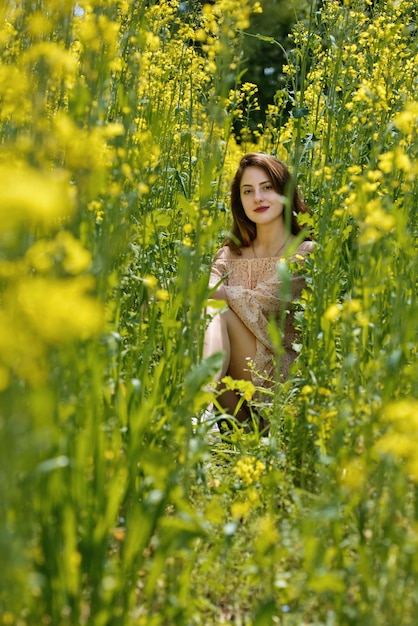 Young woman surrounded by canola flowers Spring blossom field