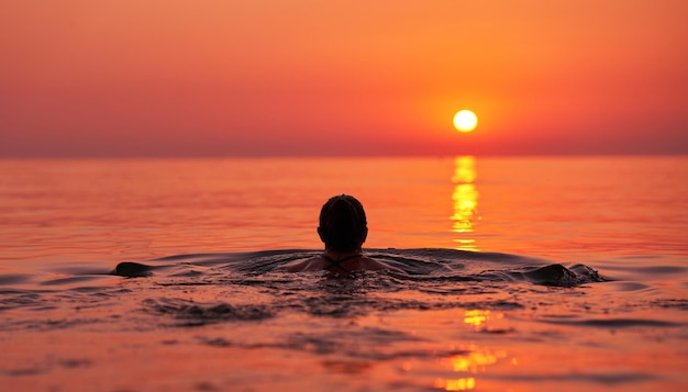 Young woman swimming in the sea on sunrise