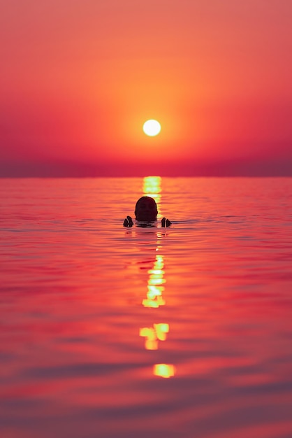 Young woman swimming in the sea on sunrise