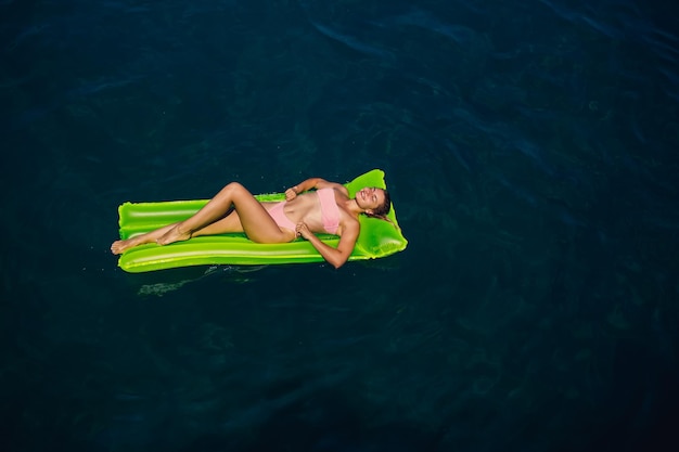 A young woman in a swimsuit swims on an inflatable bright mattress in the sea Summer vacation concept