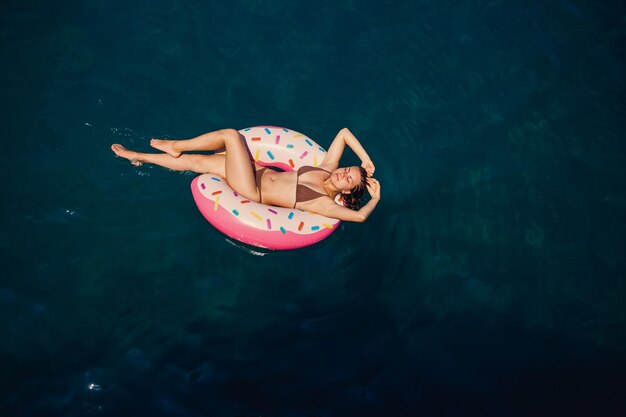 Young woman in a swimsuit swims on an inflatable ring in the sea Summer vacation concept