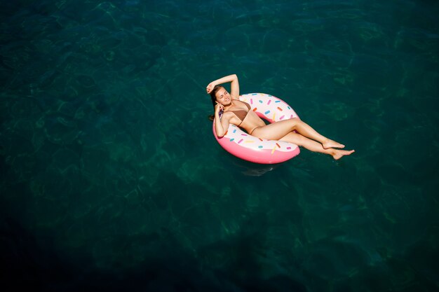 Young woman in a swimsuit swims on an inflatable ring in the sea. Summer vacation concept.