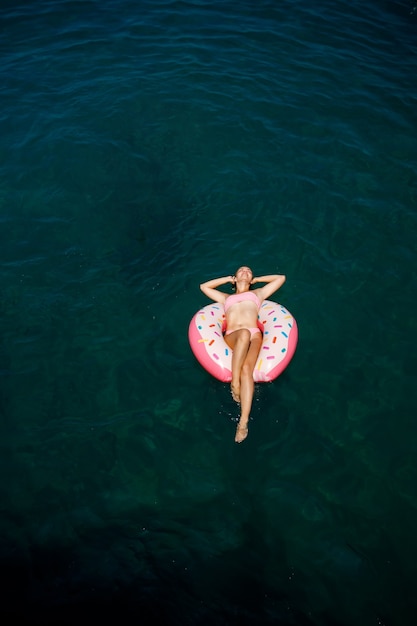 Young woman in a swimsuit swims on an inflatable ring in the sea. Summer vacation concept.