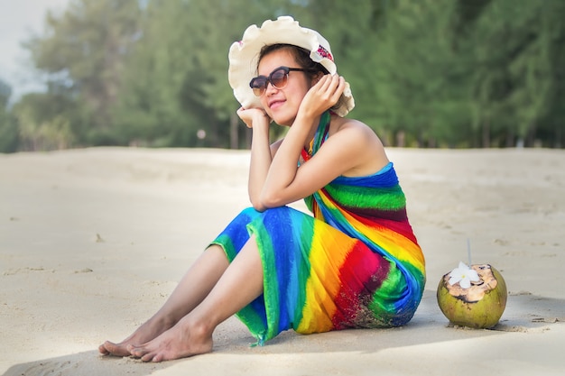 Young woman in swimsuit with coconut cocktail on the beach, Bali