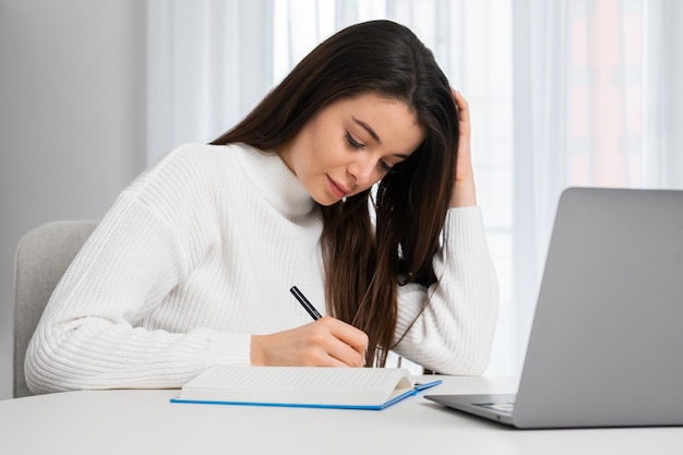 Young woman takes online courses via notebook making notes while listening to teacher attentive stud