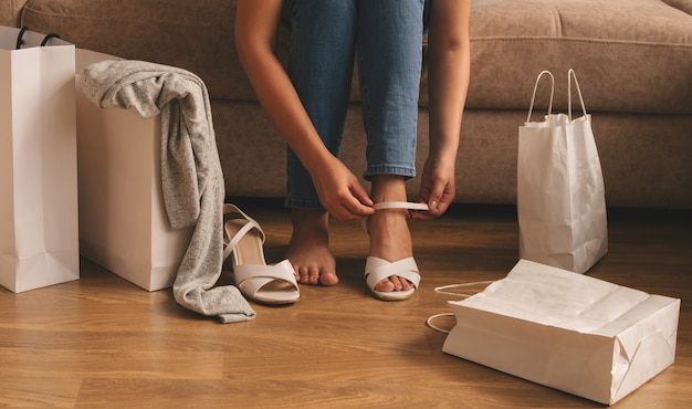 A young woman takes out her purchases from a bag while sitting on the sofa