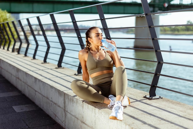 Young woman taking a break during exercise on the river promenade