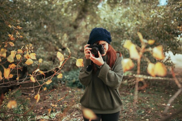 Photo young woman taking photos in the forest with an old analog camera