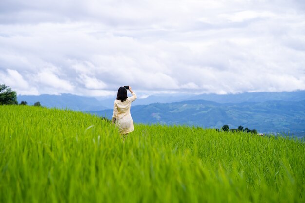 Young woman taking picture of mountain scape.