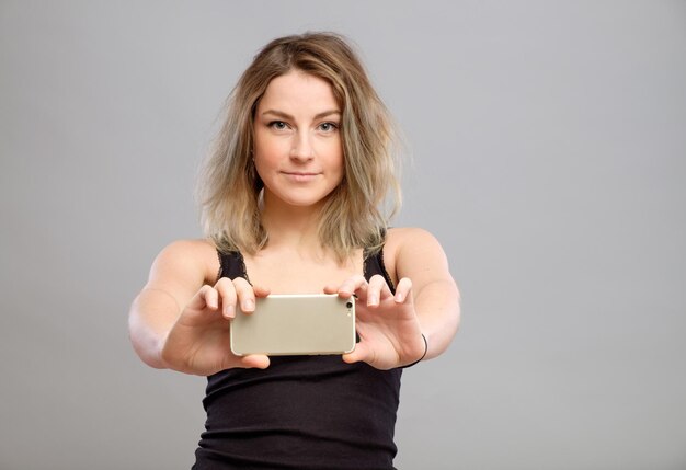 Young woman taking pictures through her phone