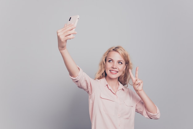 Young woman taking self photo on smartphone over grey