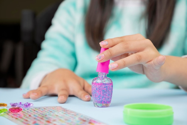 Young woman taking varnish from the bottle to paint her nails