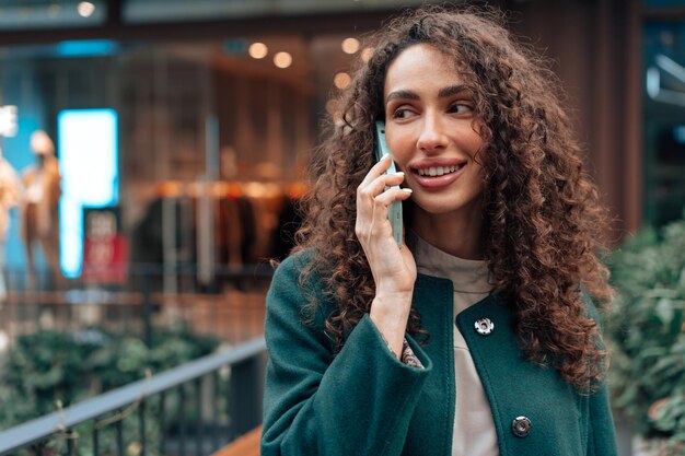 Young woman talking on mobile phone while walking in the city