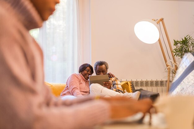 Young woman teleworking while taking care of her parents Focus on the parents using a tablet Concept family conciliation remote work health care