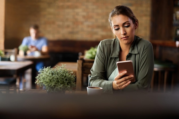 Young woman texting on mobile phone in a cafe