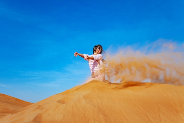 Young woman throwing sand in orande desert