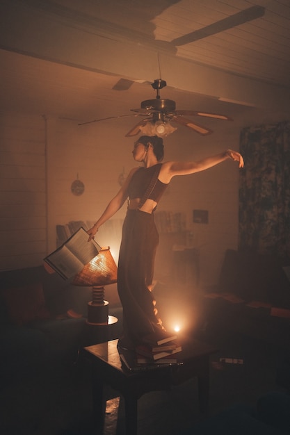 Young woman on top of a table holding a book