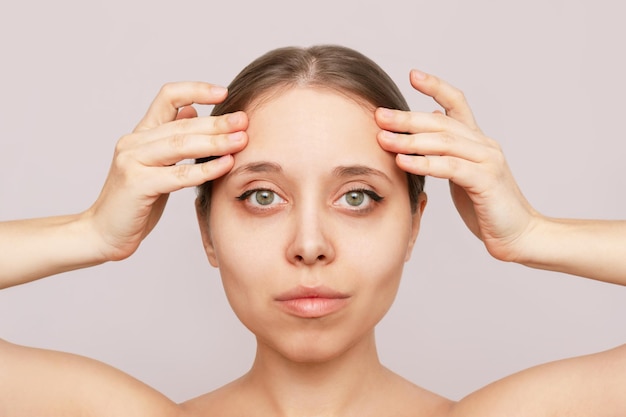 Young woman touching the forehead with her hands Result of rejuvenating botox injection lifting