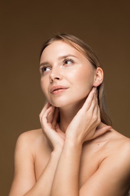 Photo young woman touching her face on brown background