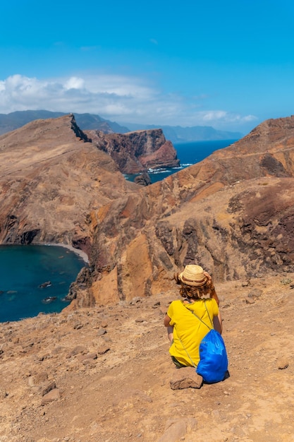 Young woman tourist sitting in summer in Ponta de Sao Lourenco looking at the landscape and the sea Madeira coast