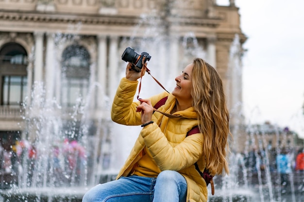 Young woman tourist takes pictures on a journey. A woman with a camera in her hands walks around the city.