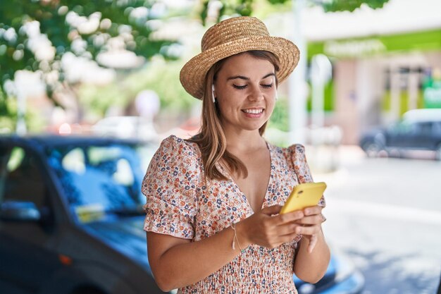 Young woman tourist wearing summer hat listening to music at street