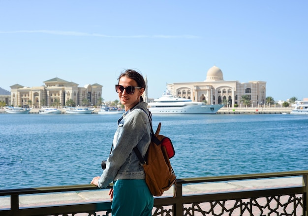 A young woman tourist with a backpack looks at the administrative region of the emirate of Sharjah