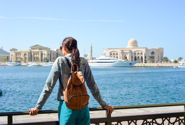 A young woman tourist with a backpack looks at the administrative region of the emirate of