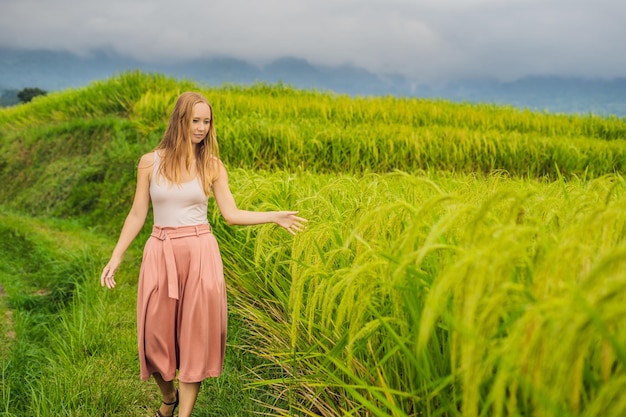 Young woman traveler on Beautiful Jatiluwih Rice Terraces against the background of famous volcanoes in Bali, Indonesia