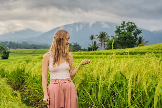 Young woman traveler on Beautiful Jatiluwih Rice Terraces against the background of famous volcanoes in Bali, Indonesia