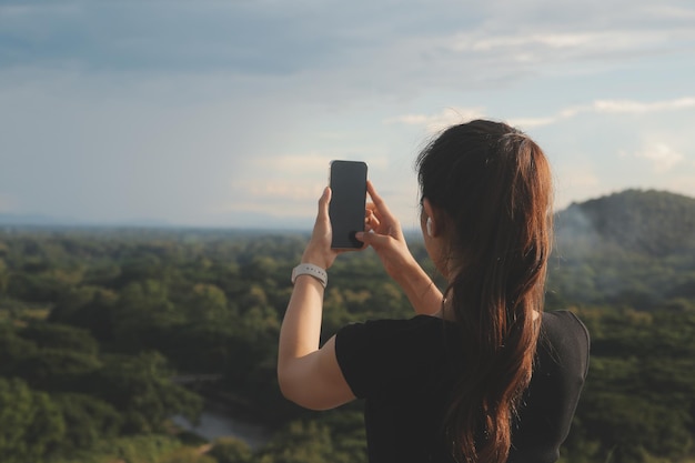 Young woman traveler in casual clothes with backpack from back on background of beautiful view on mountains