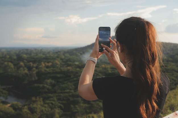 Young woman traveler in casual clothes with backpack from back on background of beautiful view on mountains