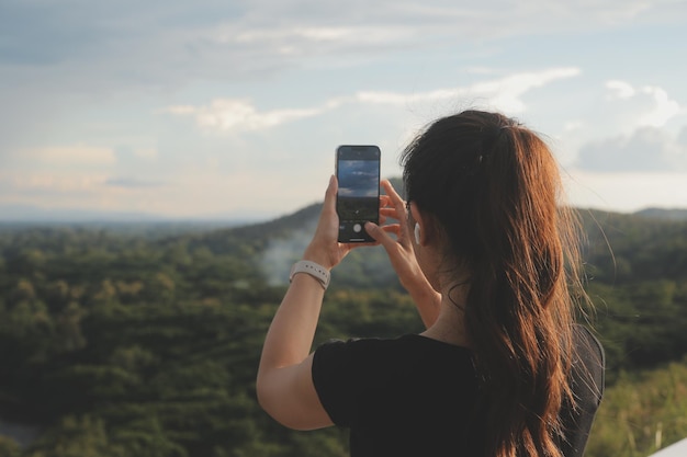 Young woman traveler in casual clothes with backpack from back on background of beautiful view on mountains