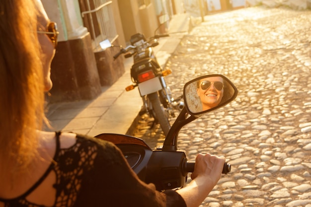 Young woman traveler driving scooter by the old city streets