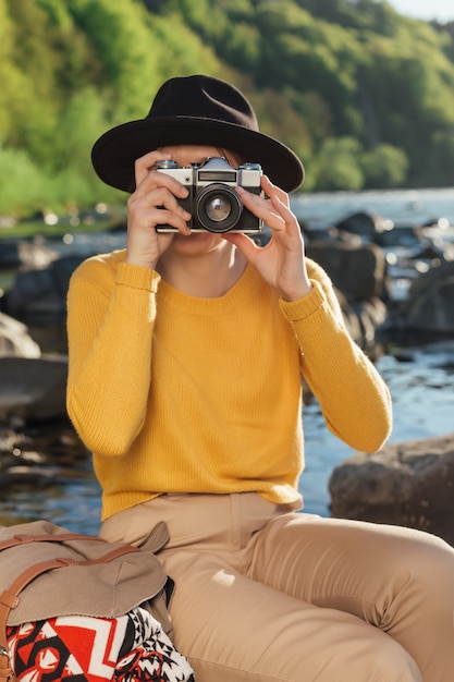 Young woman traveler is taking pictures of nature on retro camera