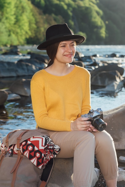 Young woman traveler is taking pictures of nature on retro camera