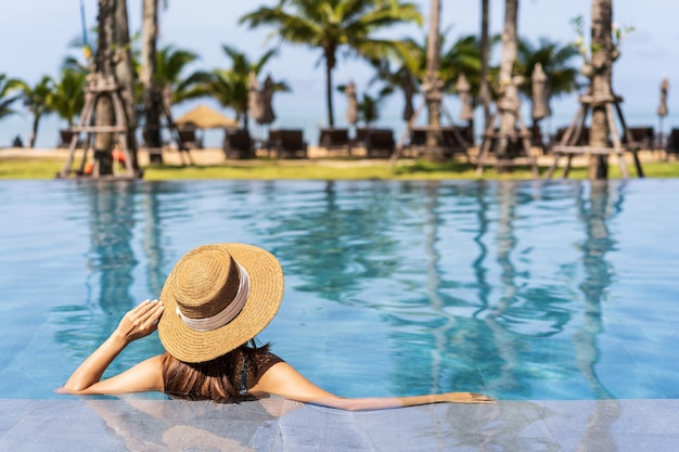 Young woman traveler relaxing and enjoying by a tropical resort pool while traveling for summer vacation, Travel concept