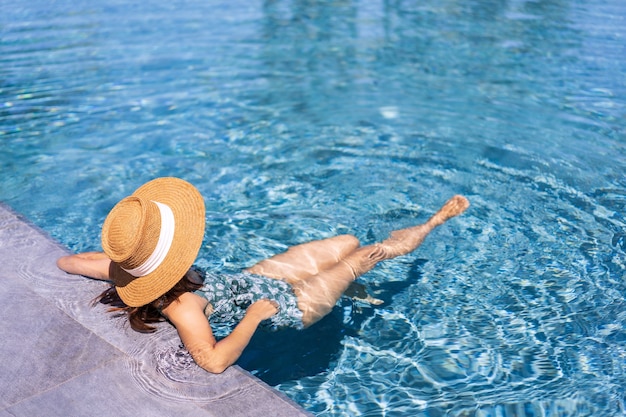 Young woman traveler relaxing and enjoying by a tropical resort pool