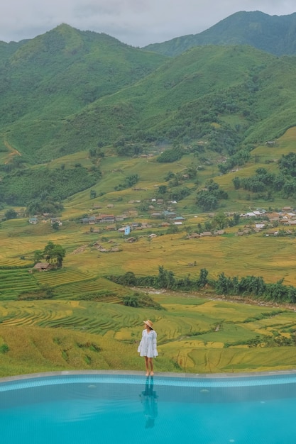 Young woman traveler relaxing at infinity pool with beautiful nature landscape mountains in Sapa Vietnam